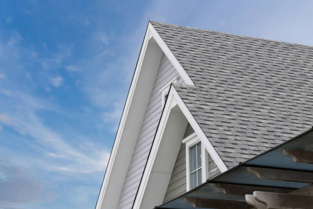 Roof shingles on top of the house against blue sky with cloud, dark asphalt tiles on the roof background.